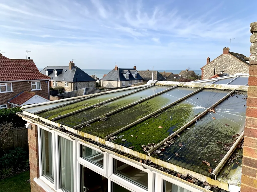 Old conservatory roof with discoloured polycarbonate sheets and debris