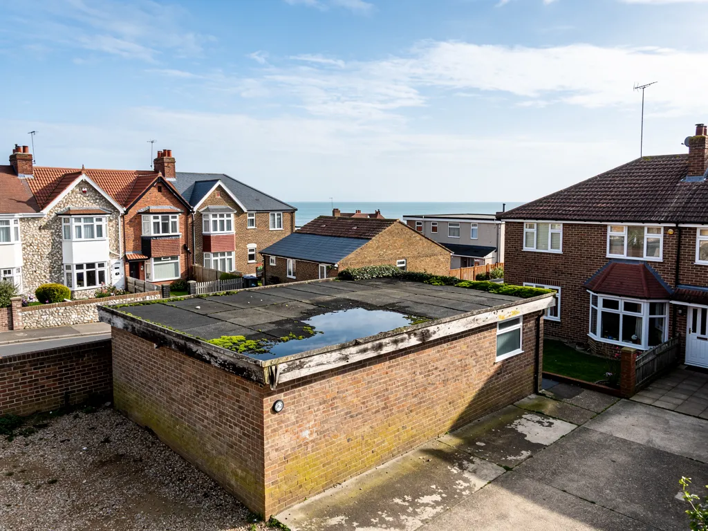 Single brick garage with a tired felt flat roof, ponding water and patches