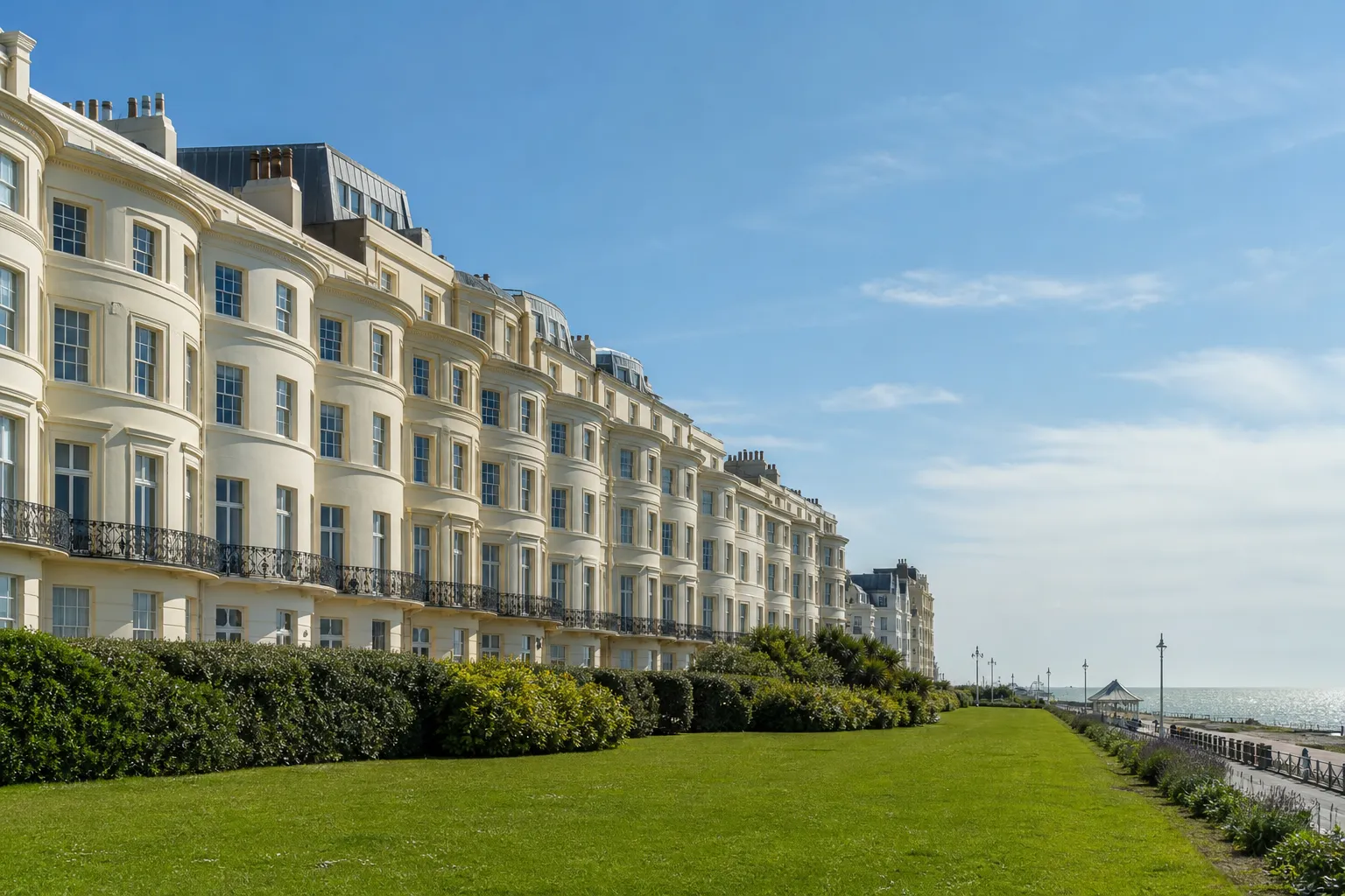 Cream stucco bow-fronted seafront terrace with flat and zinc roofs behind the parapet