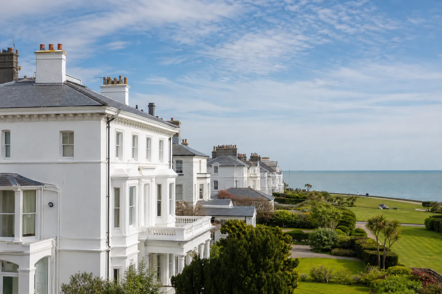 Large stucco seafront villas with slate roofs and chimneys facing the sea