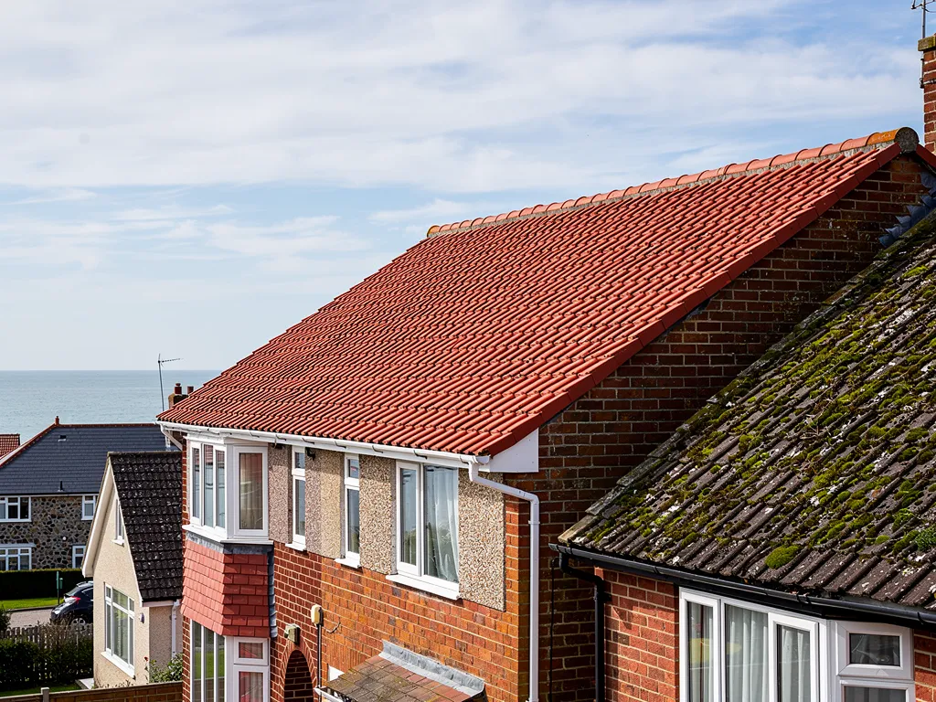 Clean clay-tiled roof after moss removal with clear gutters