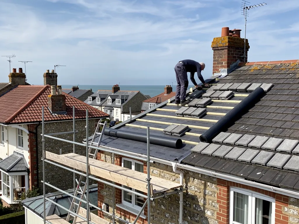 Roofer fitting a dry ridge system with screwed ridge tiles