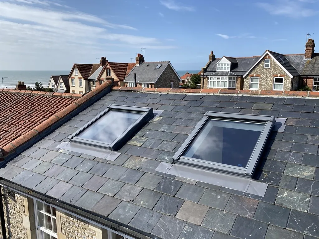 Two new roof windows with grey flashings in a slate roof